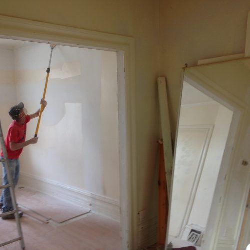painter sanding walls after drywall and plaster repairs