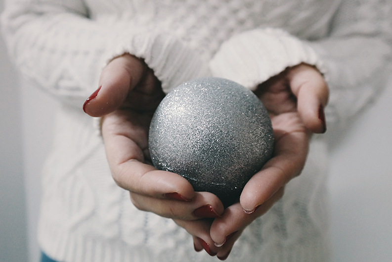 a woman holding metallic silver round ornament